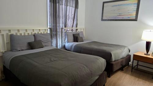 a bedroom with two beds and a lamp and a table at Stylish Urban Escape in Downtown Los Angeles in Los Angeles