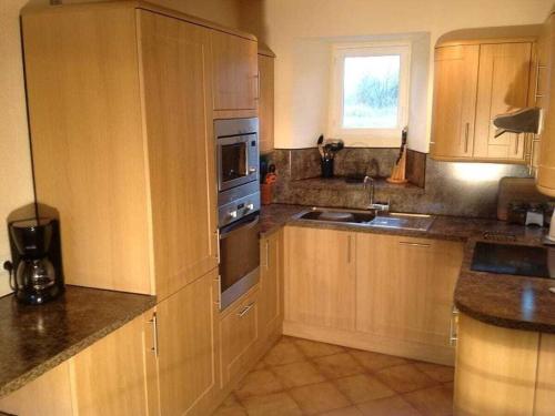 une cuisine avec des armoires en bois et des appareils en acier inoxydable dans l'établissement Holiday home with 3 bedrooms, à Neufmesnil