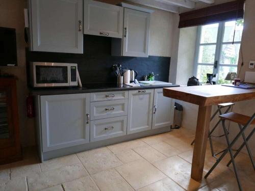 une cuisine avec des armoires blanches et un micro-ondes dans l'établissement 1-bedroom holiday apartment, à Négreville