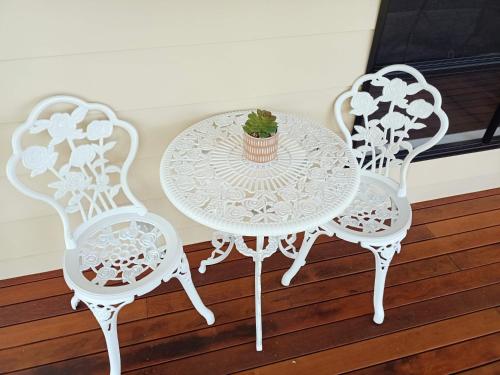 a white table with two chairs and a cactus at Suburban Paradise With a Pool in Petrie