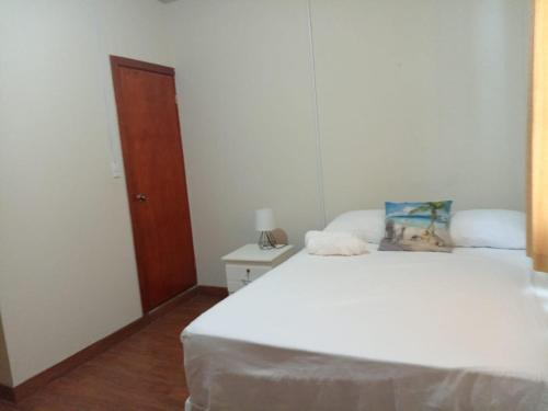 a bedroom with a white bed and a wooden door at Ibania Hostal in Tamanique