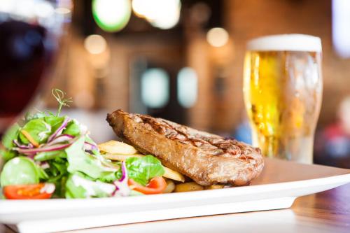 a plate with a salad and a piece of meat and a glass of beer at Nightcap at Westside Hotel in Laverton
