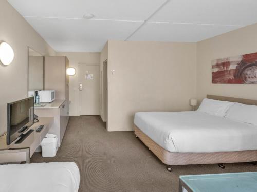 a hotel room with two beds and a television at Tall Trees Ainslie Motel in Canberra