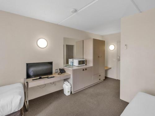 a room with a bed and a tv and a microwave at Tall Trees Ainslie Motel in Canberra