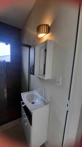 a small bathroom with a white sink and a light at Apartamento de dois quartos centro de Pomerode in Pomerode