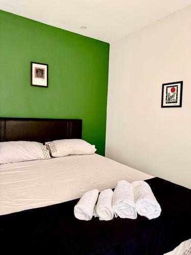 a bedroom with a green wall and a bed with three pillows at Loft Vava in Campina Grande
