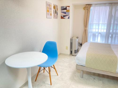 a bedroom with a bed and a table and a blue chair at Endless Mitsui Minami 5jo II in Sapporo