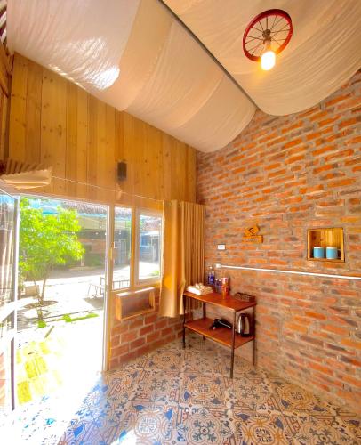 a room with a table and a brick wall at Homestay Gấu Smile - Mộc Châu in Sơn La