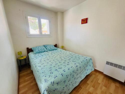 une chambre avec un lit avec une couette bleue et une fenêtre dans l'établissement Argelès-Plage - T2 à 50m de la plage, 4 pers, centre-ville - FR-1-309-399, à Argelès-sur-Mer