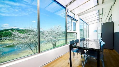 a dining room with a table and chairs and large windows at Gapyeong Eco Healing Pool Villa Pension in Gapyeong