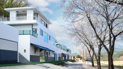 a white building with trees in front of it at Gapyeong Eco Healing Pool Villa Pension in Gapyeong