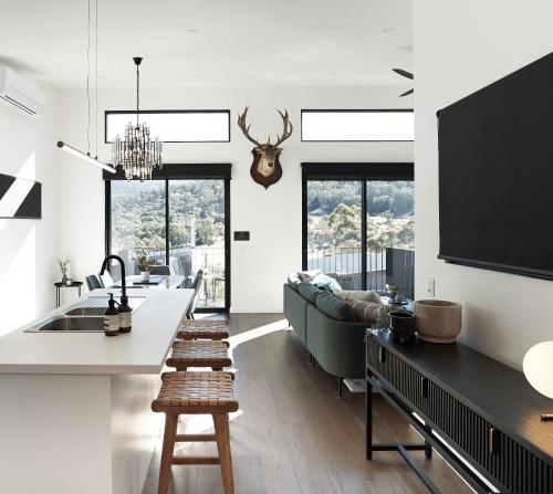 a kitchen and living room with a couch and a table at PISTE LUXURY CHALET - THE PETITE - Oaks Lake Crackenback Resort in Crackenback