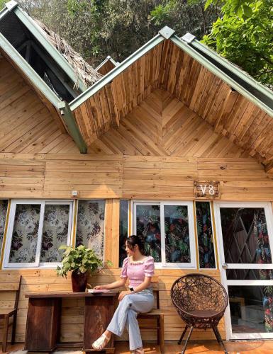 a woman sitting on a bench in front of a house at Homestay Gấu Smile - Mộc Châu in Sơn La