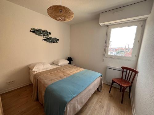 une chambre avec un lit, une chaise et une fenêtre dans l'établissement Appartement T3 en Bord de Mer à Arcachon avec Parking Sécurisé - FR-1-374-235, à Arcachon