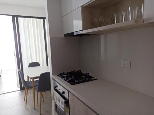 a kitchen with a stove top oven next to a table at Apartamento Moderno a Estrenar con Excelente Ubicación Santa Marta in Gaira