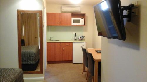 a small kitchen with a table and a television on a wall at Willows Motel in Goulburn