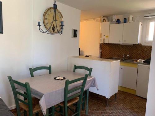 une cuisine avec une table et des chaises et une horloge au mur dans l'établissement Charmant T2 proche plage, 4 pers., WIFI, parking - FR-1-607-223, au Cap d'Agde