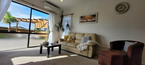 a living room with a couch and a chair and a window at Elevated Family Sized Guest-house with Beautiful Views in Auckland