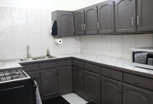 a kitchen with gray cabinets and a sink and a microwave at Villa Solara Your Spacious, Central, Affordable Stay in Kingston in Kingston