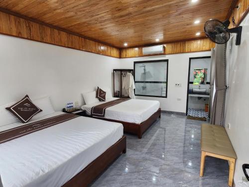 a hotel room with two beds and a table at Tam Coc Kamili Bungalow & Homestay in Ninh Binh