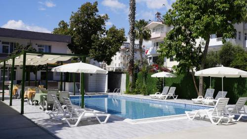 a swimming pool with chairs and umbrellas next to a building at Hillside Apart House in Side