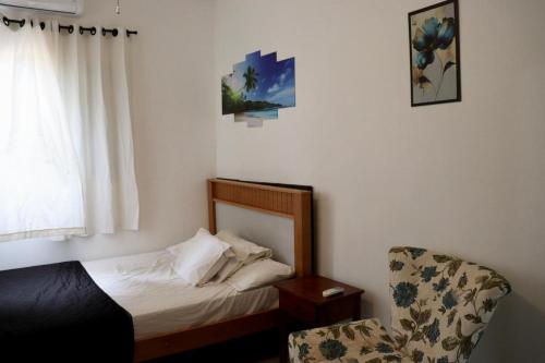 a small bedroom with a bed and a chair at Mini Casa Família in Brotas