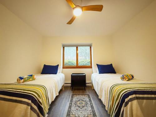 two beds in a room with a ceiling fan at Peaceful Retreat on Chilton Lane in Brewster