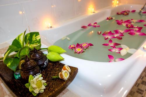 a bath tub filled with water with flowers in it at Golden Orchid Angkor in Siem Reap