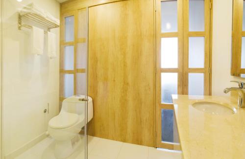 a bathroom with a toilet and a sink and a window at Hotel Camino de la Sal in Zipaquirá
