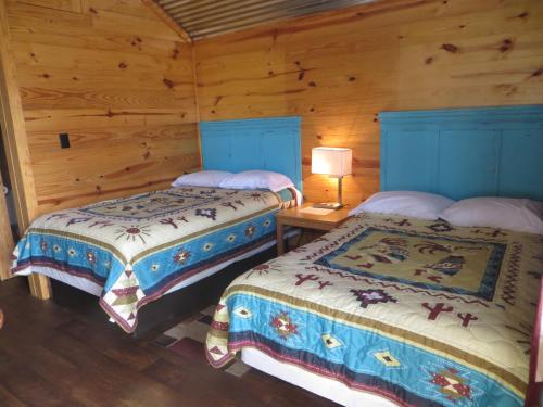 two beds in a room with wooden walls at All Tucked Inn Cabins in Stockdale