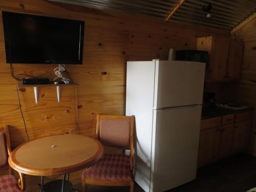 a kitchen with a table and a white refrigerator at All Tucked Inn Cabins in Stockdale