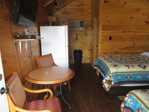 a room with a table and a refrigerator and a bed at All Tucked Inn Cabins in Stockdale