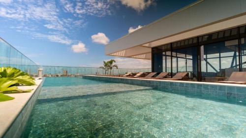 a swimming pool with chairs and a building at Studio Beira-mar, rooftop com piscina e jacuzzi in Fortaleza