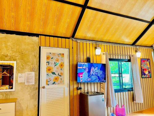 a kitchen with a refrigerator and a tv on the wall at The Lofthouse Sansai in Chiang Mai
