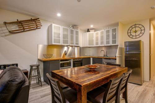 a kitchen with a wooden table with chairs and a clock at Lantern 34 - 2 Bedroom Terrace in Thredbo
