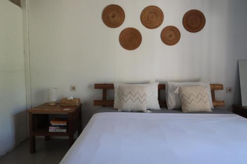a bedroom with a bed with pillows and a table at Kayu Cottage in Gili Trawangan