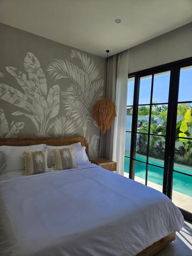 a bedroom with a large bed with a large window at White Shell Villas in Uluwatu