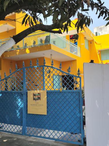 a yellow building with a blue gate and a tree at The Nomad cave in Lucknow