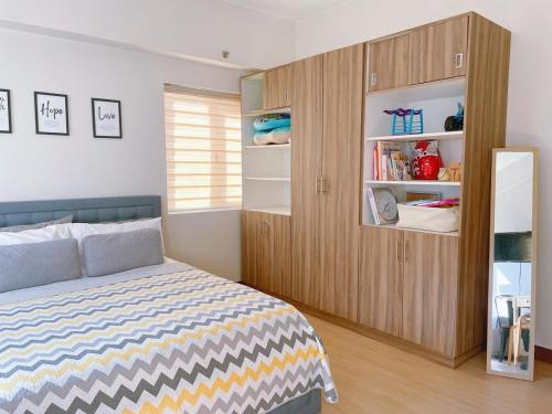 a bedroom with a bed and a wooden cabinet at Eco Suite Hope Residences Trece in Trece Martires