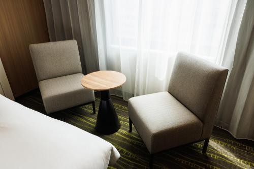 a hotel room with two chairs and a table and a bed at JR-East Hotel Mets Shibuya in Tokyo