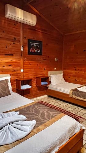 two beds in a room with wooden walls at Myland Nature in Cıralı