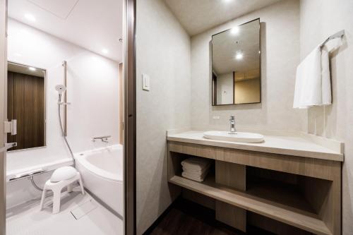 a bathroom with a sink and a tub and a toilet at JR-East Hotel Mets Shibuya in Tokyo
