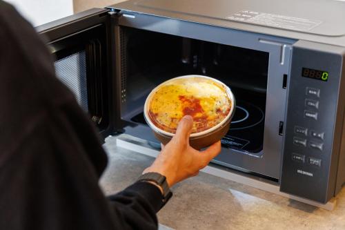 a person holding a dish of food in a microwave at JR-East Hotel Mets Shibuya in Tokyo