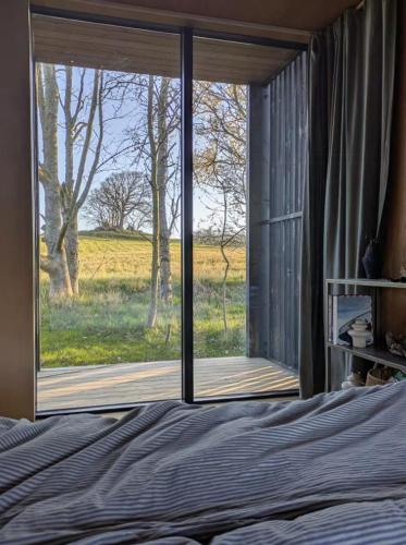 a bedroom with a bed and a large window at Tiny House Overlooking Nature in Vordingborg
