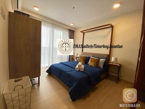 a bedroom with a blue bed with a large mirror at EMAS Suite Timurbay, Kuantan in Kuantan