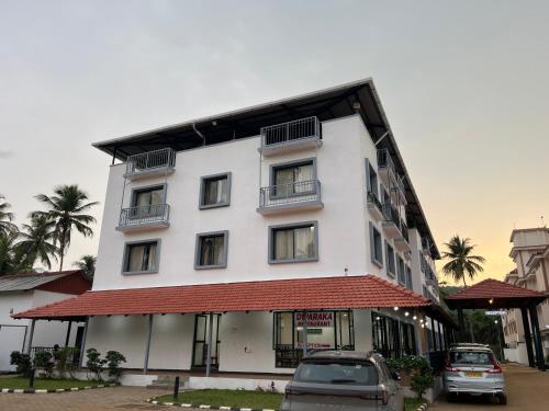 a white building with cars parked in front of it at HOTEL DWARA in Subrahmanya