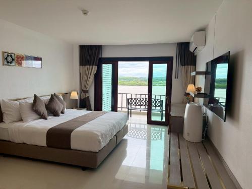 a bedroom with a large bed and a balcony at Siam Triangle Hotel Chiang Sean in Chiang Saen