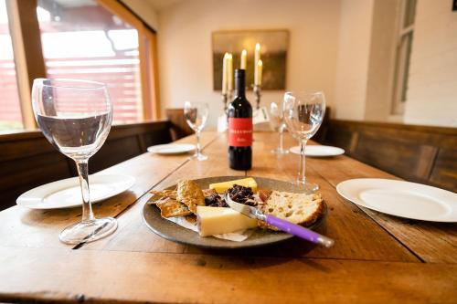 a wooden table with a plate of food and wine glasses at The Residence of MacKenzie Quarters CBD Bendigo in Bendigo