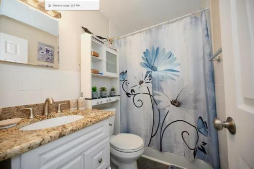 a bathroom with a shower curtain with a blue flower on it at Villa On The Ocean in Fort Pierce
