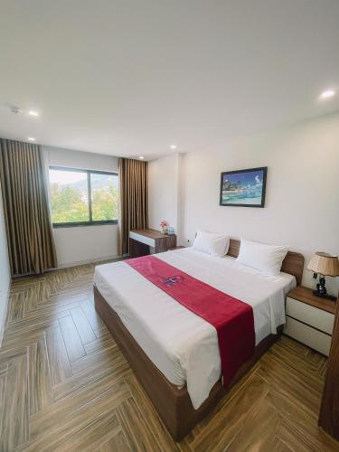 a bedroom with a large bed and two windows at Blue Sea Hotel in Cam Lâm